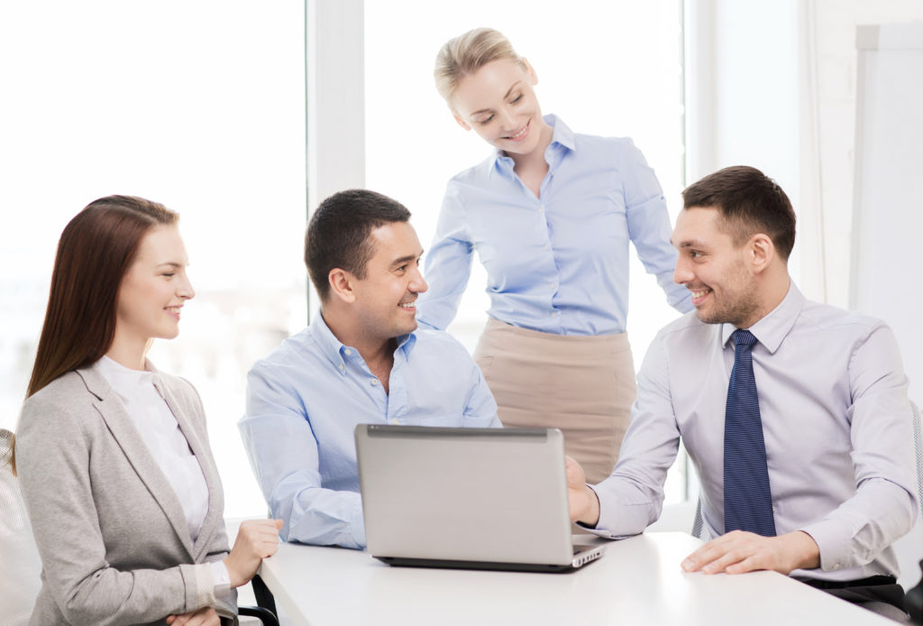 business and office concept - smiling business team working with laptop computer in office